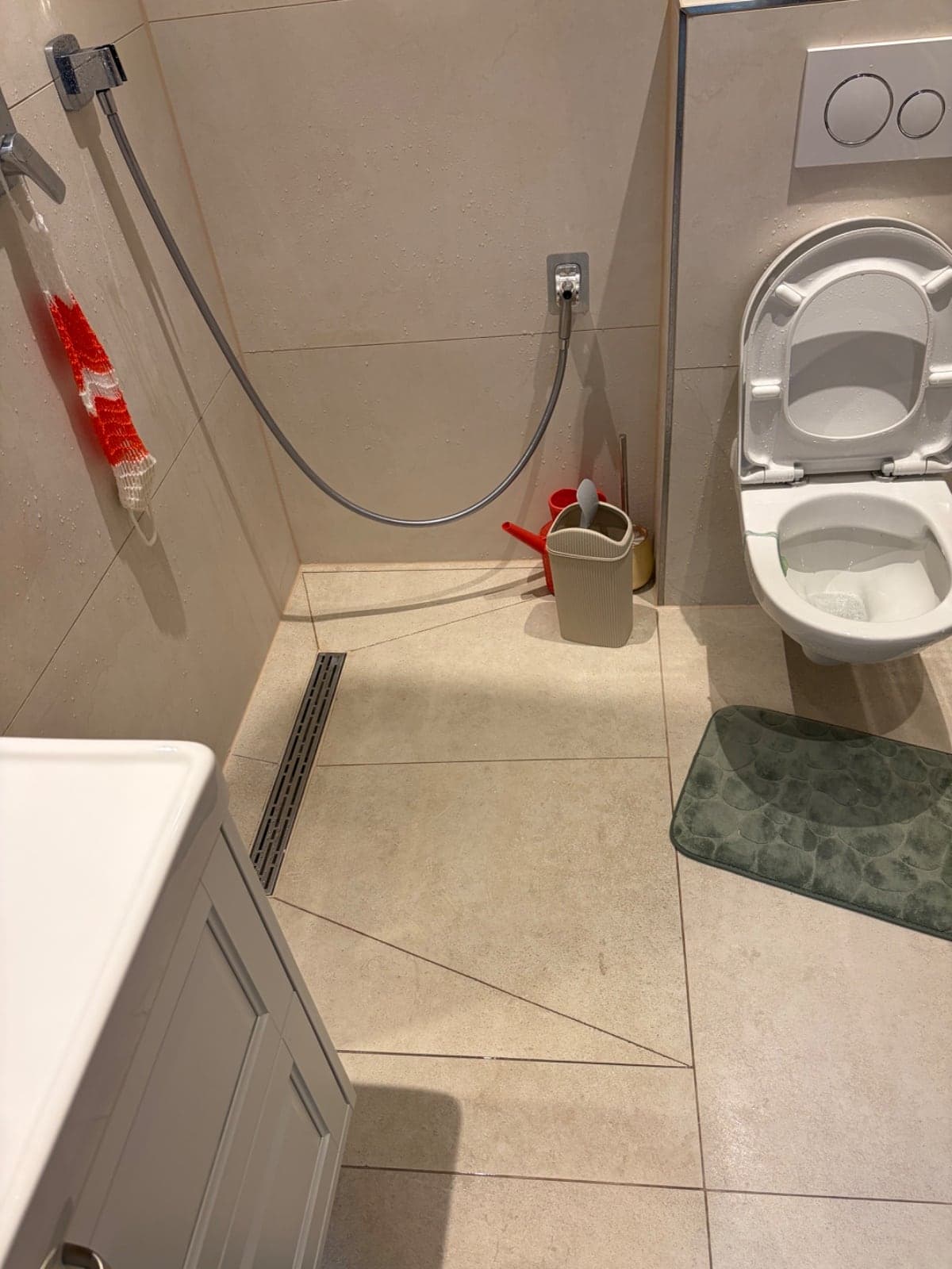 Fertiggestellte bodengleiche Dusche mit großformatigen beigen Fliesen und Wand-WC