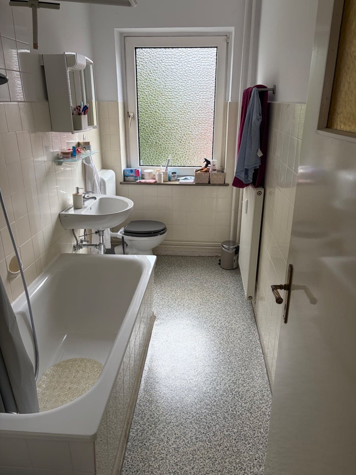 Älteres Badezimmer vor der Sanierung mit Wanne und kleinformatigen Fliesen