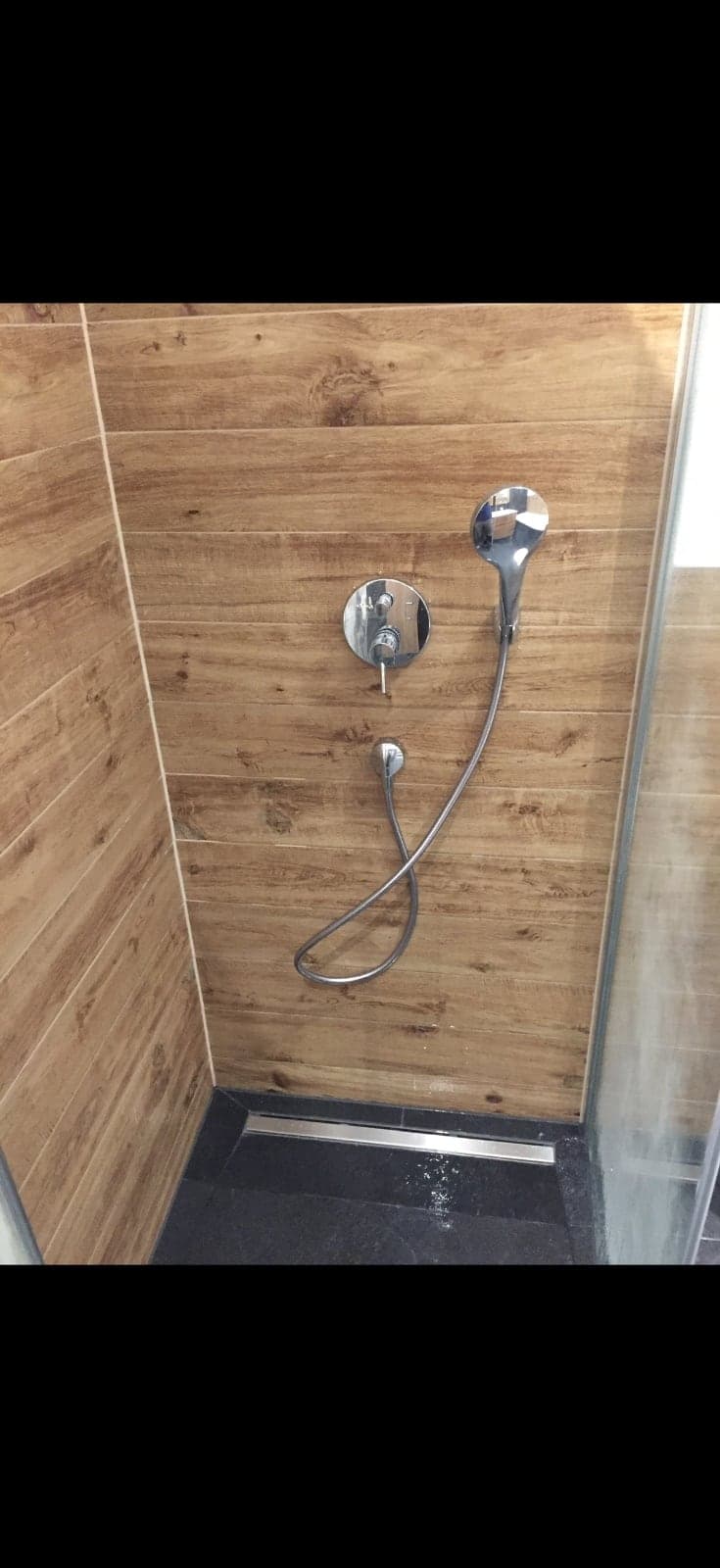 Fertige Dusche mit holzoptischen Fliesen und Glasabtrennung