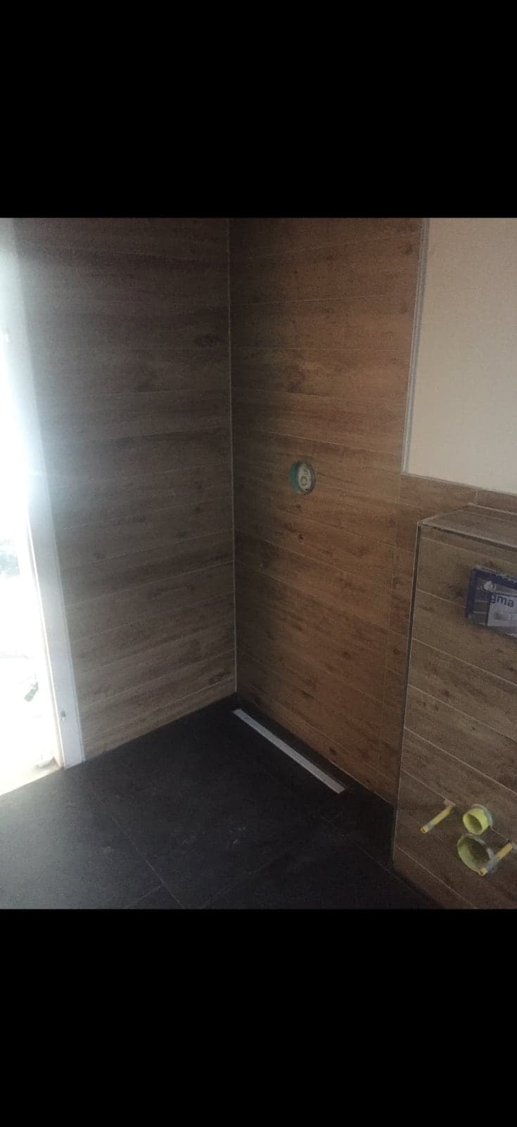 Duschbereich mit holzoptischen Fliesen vor Fertigstellung der Bodenrinne