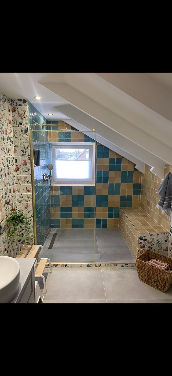 Gesamtansicht der bodengleichen Dusche mit Dachschräge, gefliester Sitzbank und Glasabtrennung