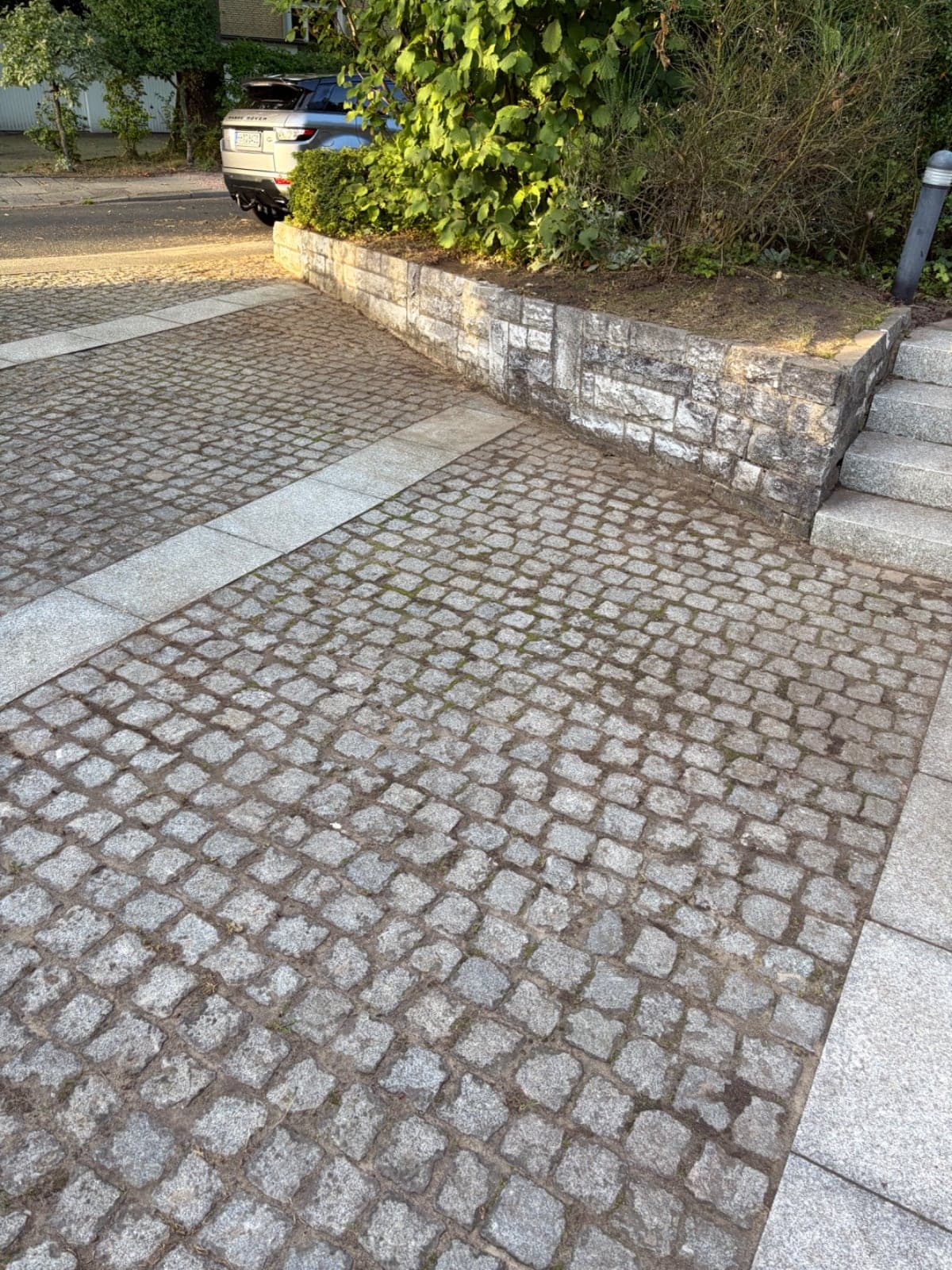 Weitwinkelansicht der neu gepflasterten Einfahrt mit Bepflanzung