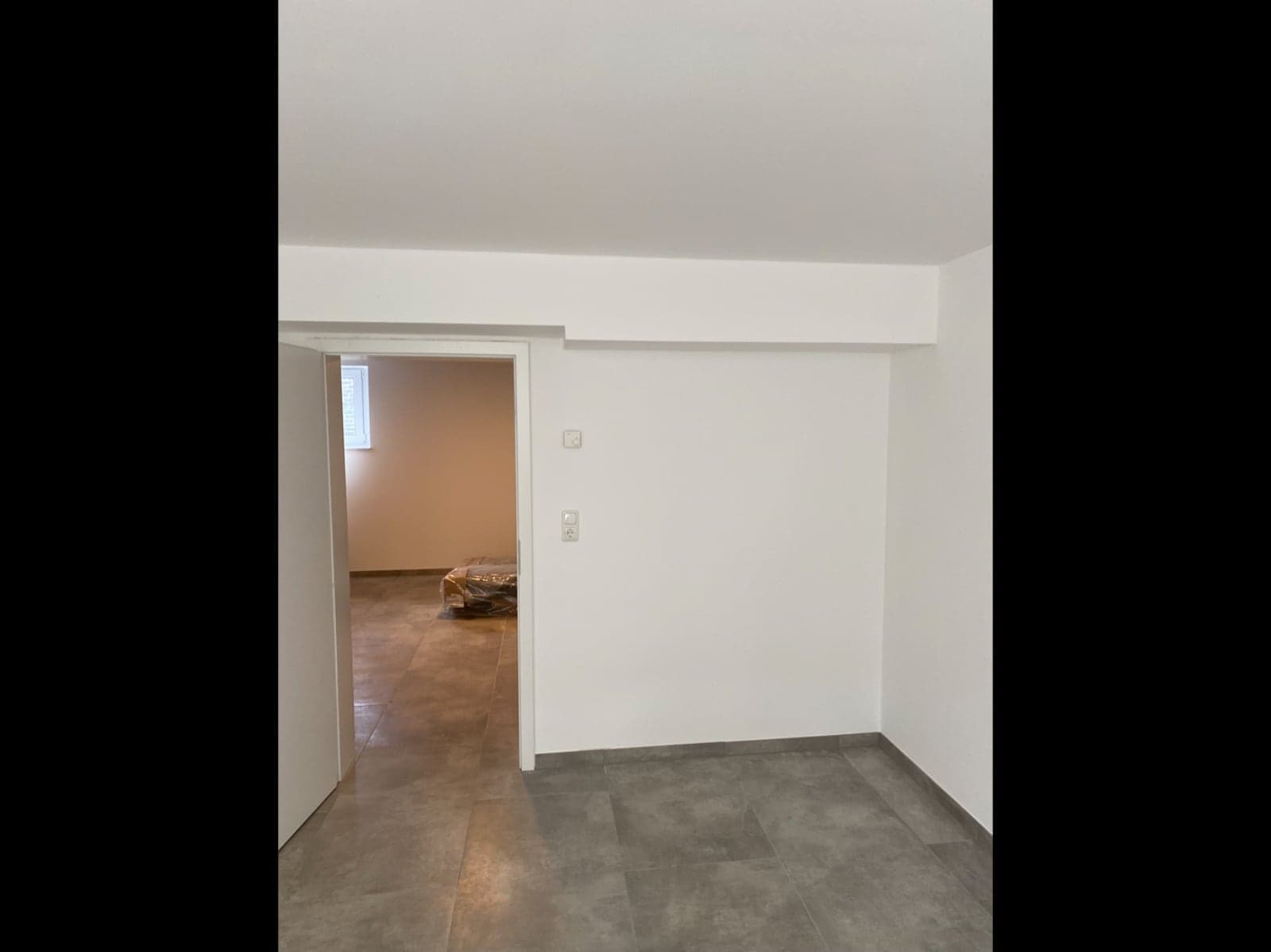 Fertiggestellter Raum mit dunklem Fliesenboden und weißen Wänden