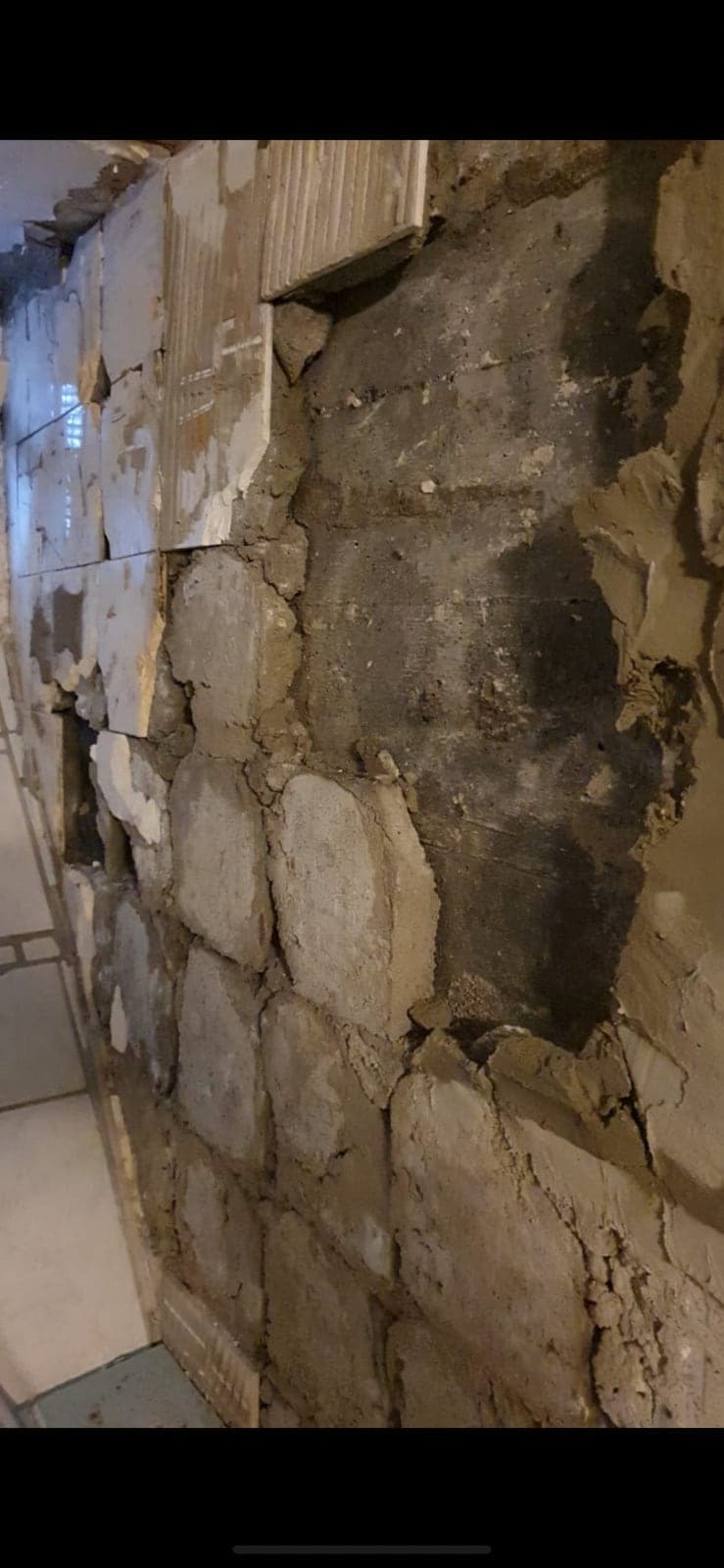 Freigelegte Wand mit Feuchtigkeitsspuren nach Entfernen alter Fliesen
