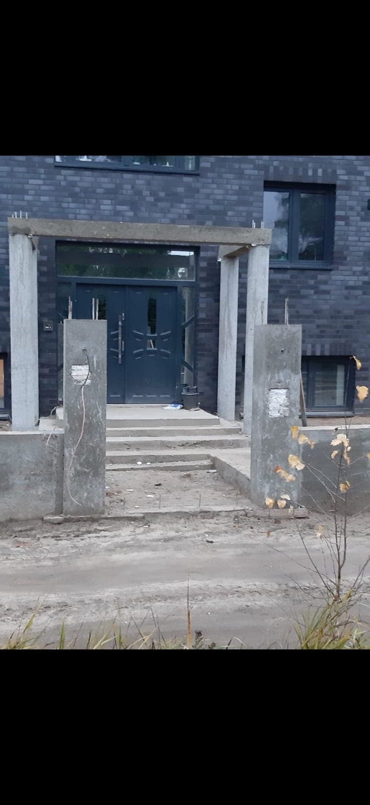 Hauseingang im Rohbau mit Betonstützen vor einer Klinkerfassade