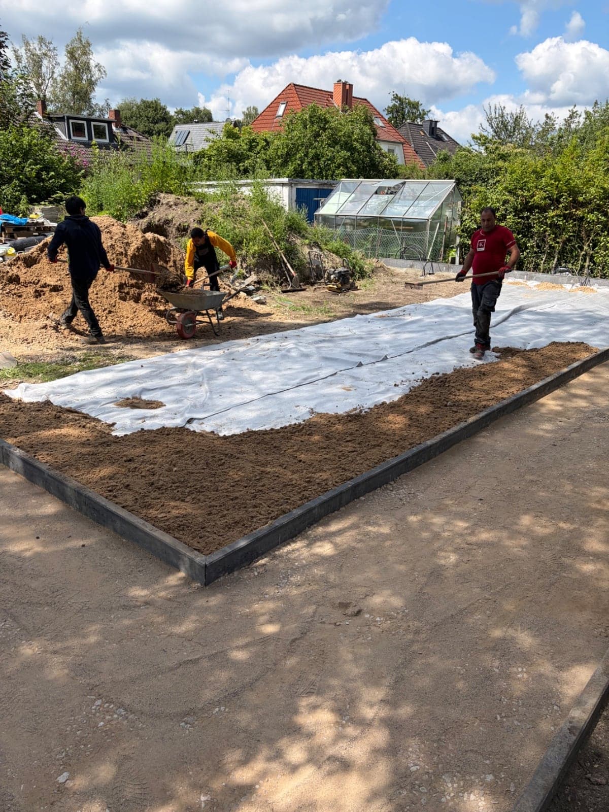 Verlegung von Vlies und Sand für das Pflasterbett im Team