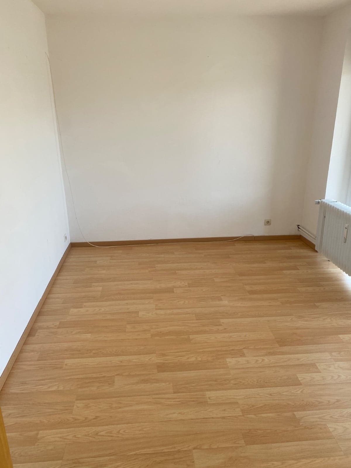 Leerer, frisch renovierter Raum mit neuem Laminatboden und weißen Wänden
